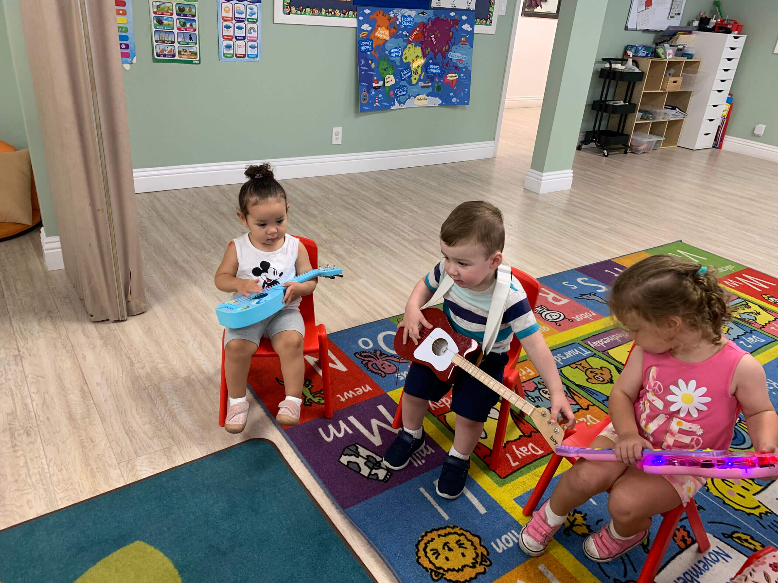 Toddlers sitting around at daycare holding kid-friendly instruments, ready for a music activity.