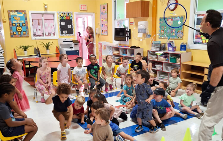 Guest performer demonstrating a bubble activity in front of a preschool classroom filled with engaged children.