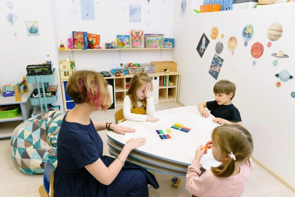 Preschool teacher at Firehouse School working with young children at an activity table, teaching colors during a hands-on early learning activity.